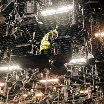 Production Arts student in hard hat and high-vis vest walking across the tension wire grid
